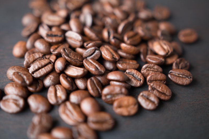 A bag of whole coffee beans with beans spilling onto a table